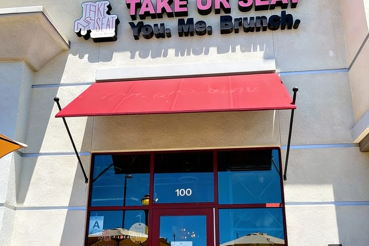 Exterior of Take Ur Seat in Chino Hills, with its red awning and 'You, Me, Brunch' storefront sign.