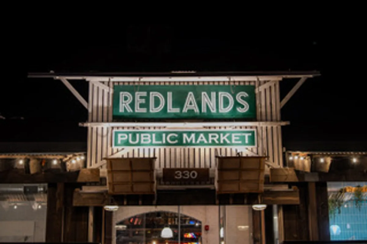 The illuminated Redlands Public Market sign above the entrance to the downtown food hall where Take Ur Seat Lite serves.
